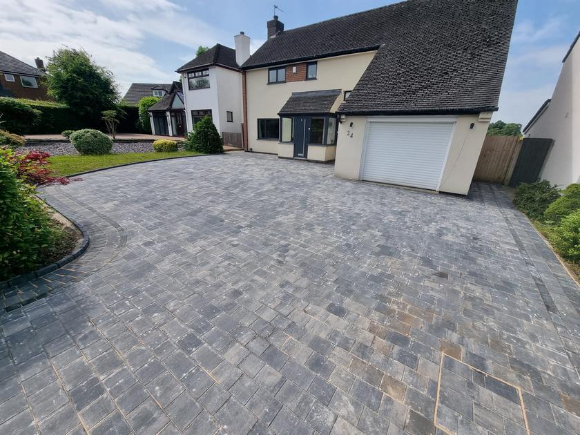 Large charcoal block paved driveway sweeping up to a detached house