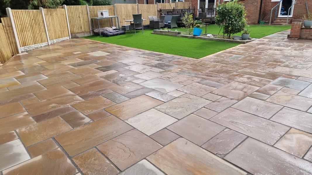 Indian sandstone patio in mixed sizes with an artificial lawn beyond